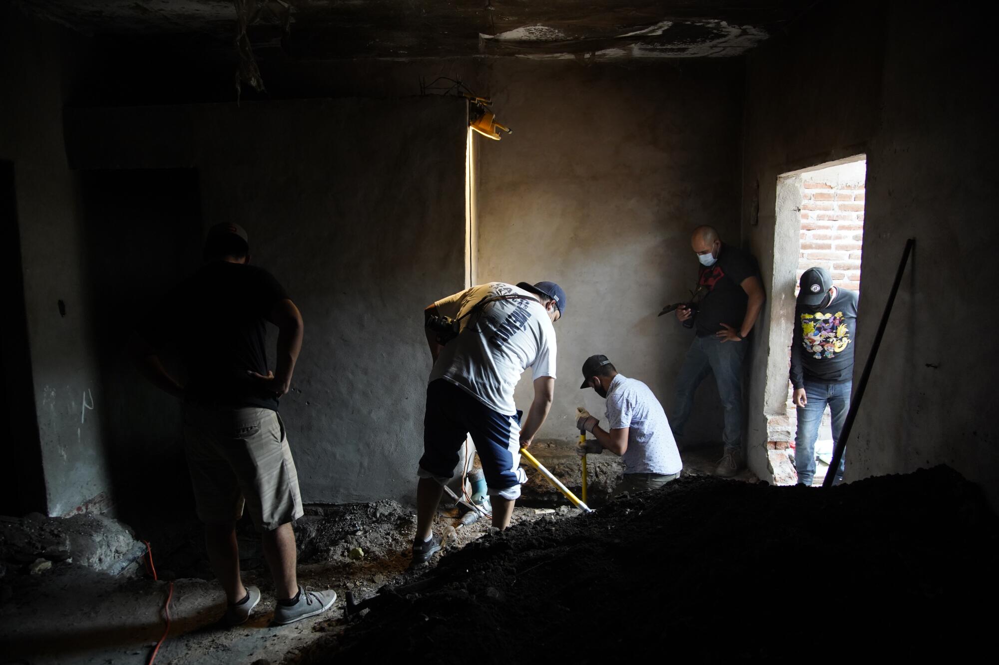 People dig for bodies inside a house.