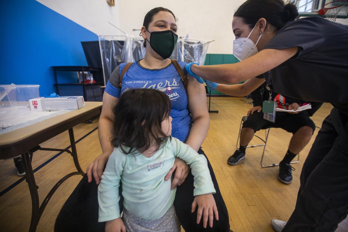 A woman holding a child gets vaccinated
