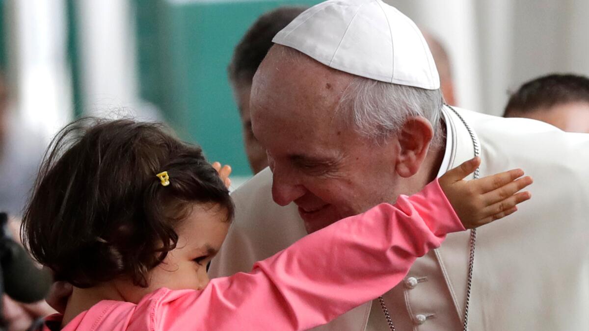 Pope Francis hugs a child Wednesday on the outskirts of Rome.