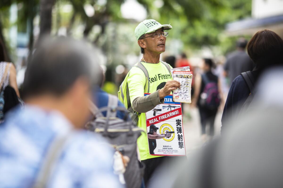 A leaflet distributor for the Waikiki Gun Club works the sidewalk outside a shopping complex in Honolulu.