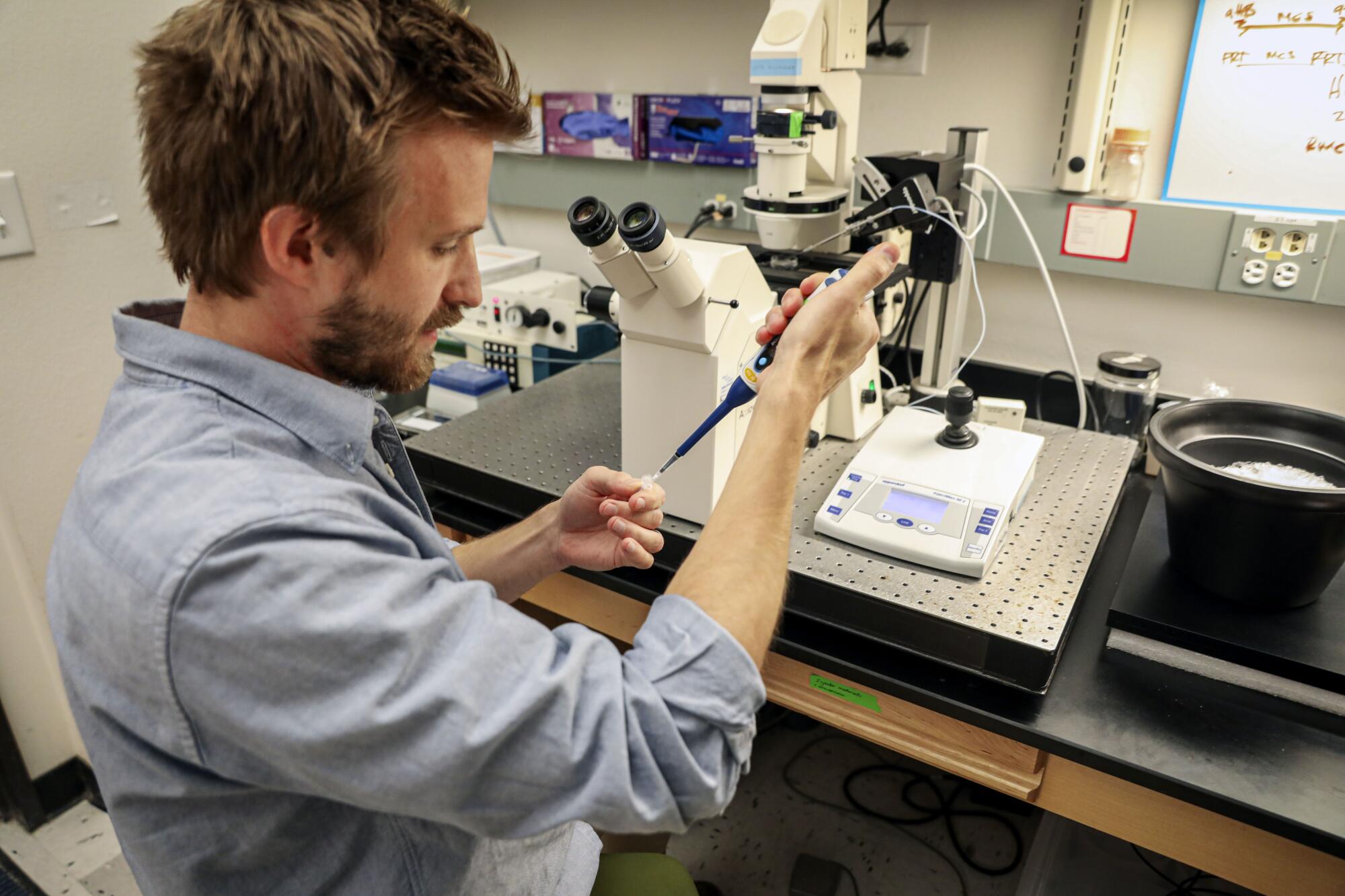 Elliot Jackson, a postdoctoral researcher, works with sea urchin eggs in a lab at Scripps