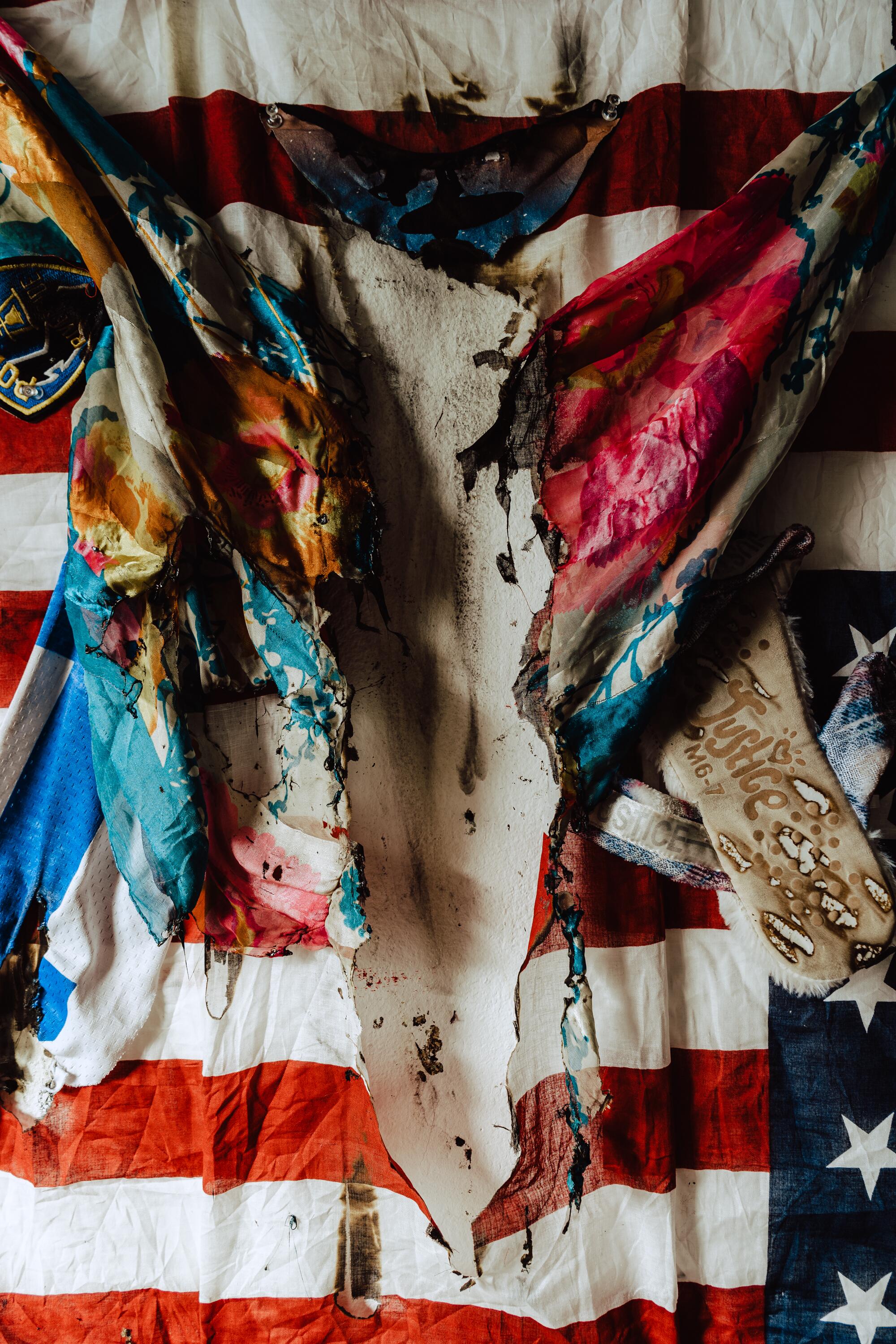 Muna Malik Recycled Democracy Found materials collage 37 x 35 U.S Flag, slipper, t-shirt, police patch