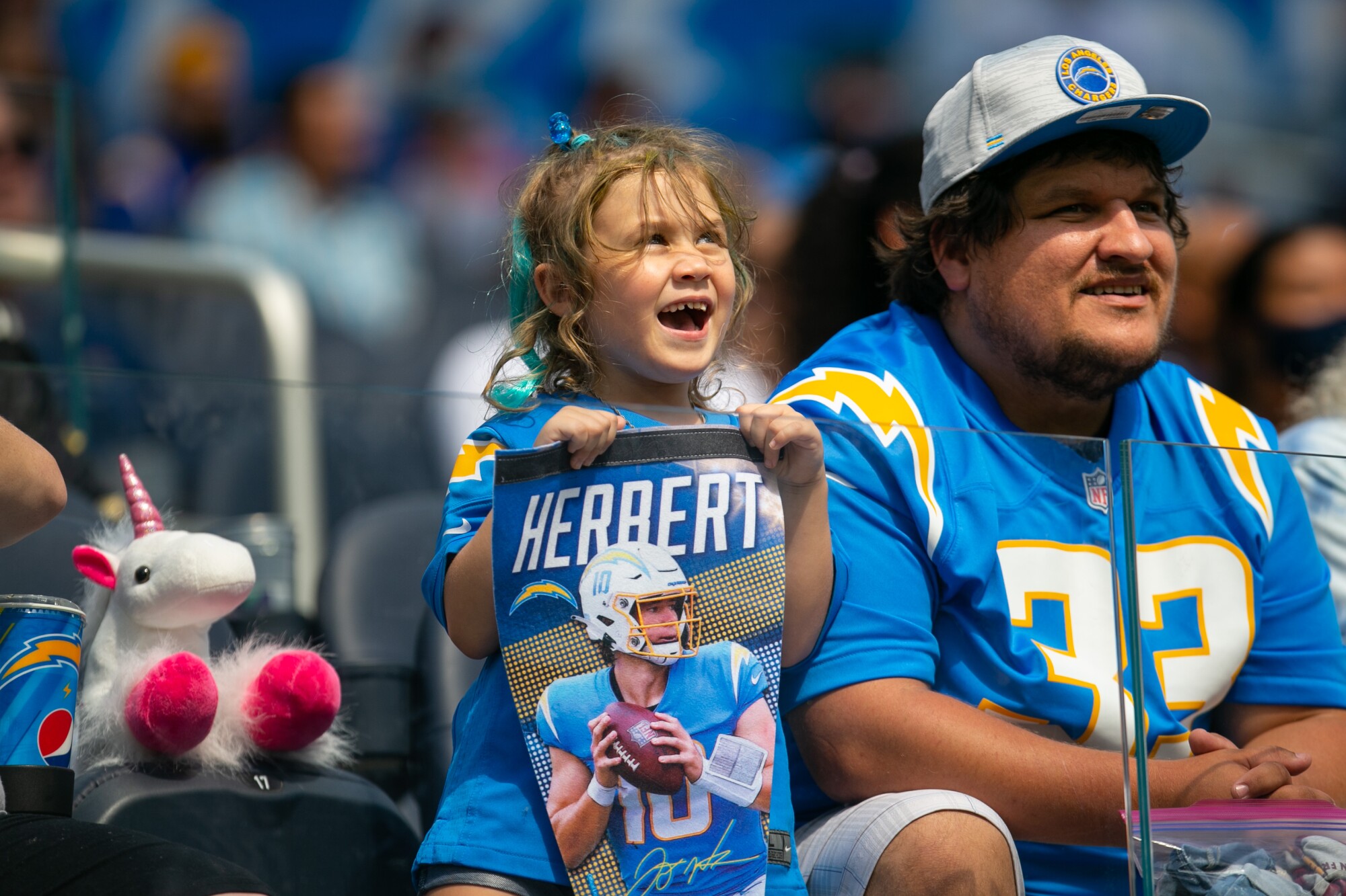 A young girl holds a pennant of quarterback Justin Herbert.