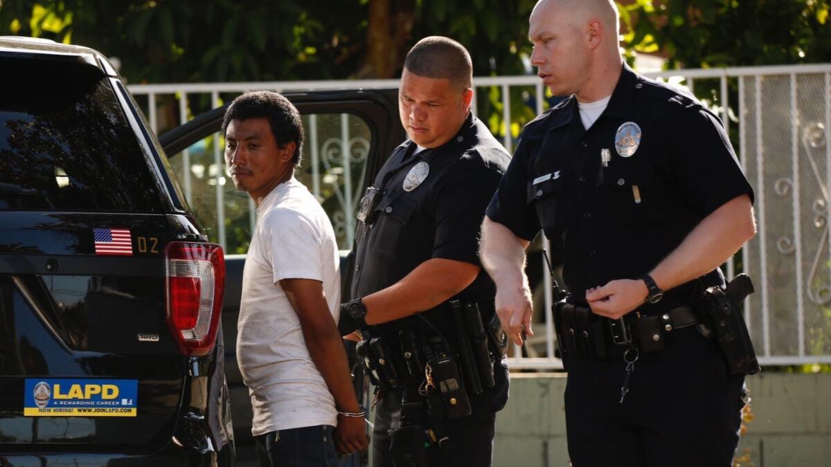 Police detain a suspect near the 400 block of Heliotrope Drive in East Hollywood on Monday morning.