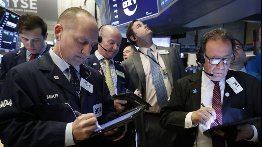 Traders gather at the post that handles Oaktree Capital Group on the floor of the New York Stock Exchange on Wednesday.