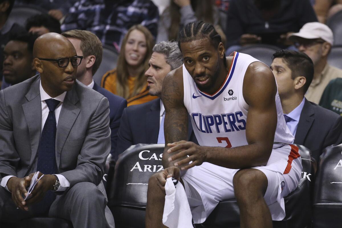 Clippers assistant coach Sam Cassell sits with Kawhi Leonard during a loss to the Suns on Oct. 26, 2019, in Phoenix.
