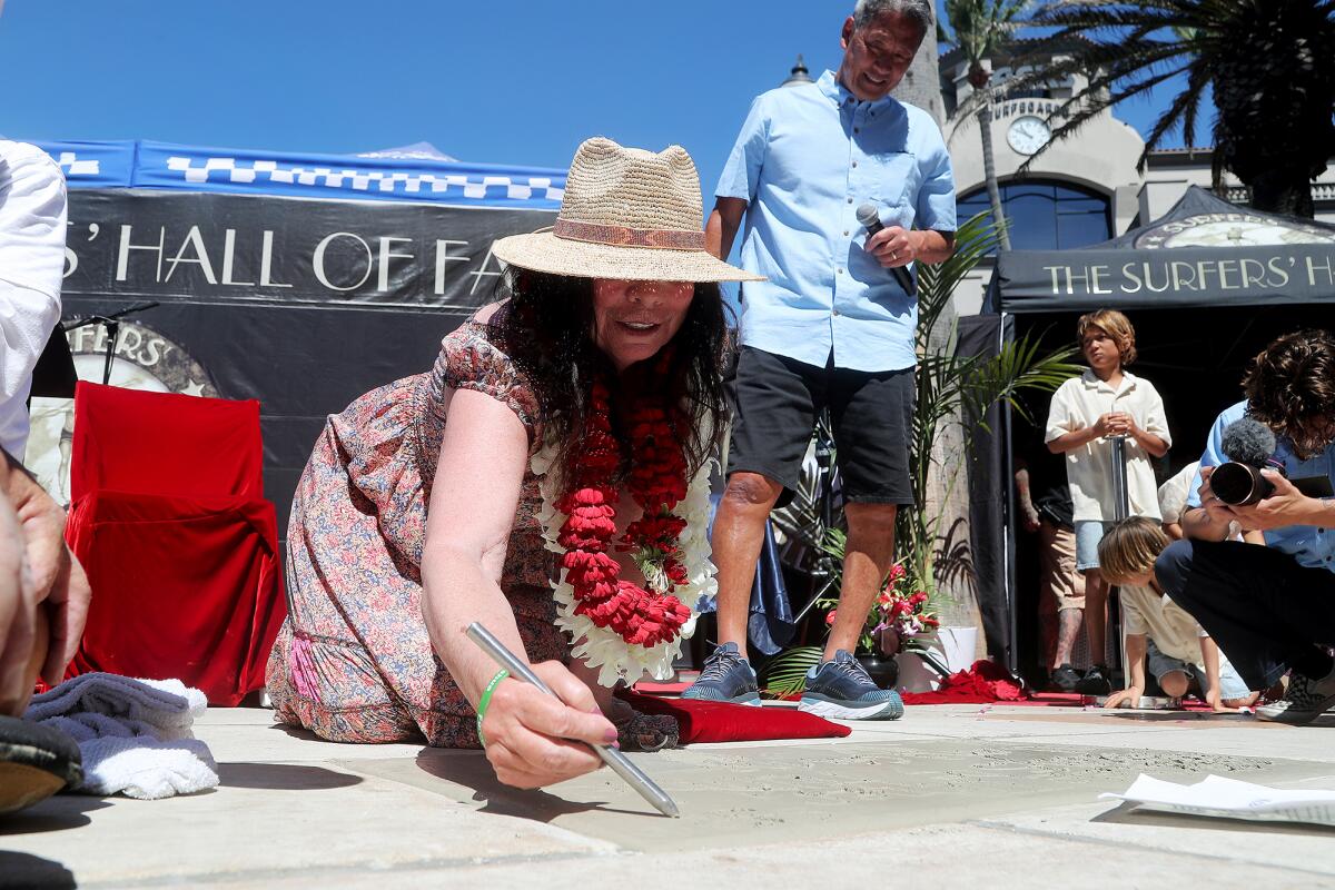 Inductee Michele Turner, Sugar Shack Cafe owner, inscribes her name and a message into her slab of wet cement Friday.