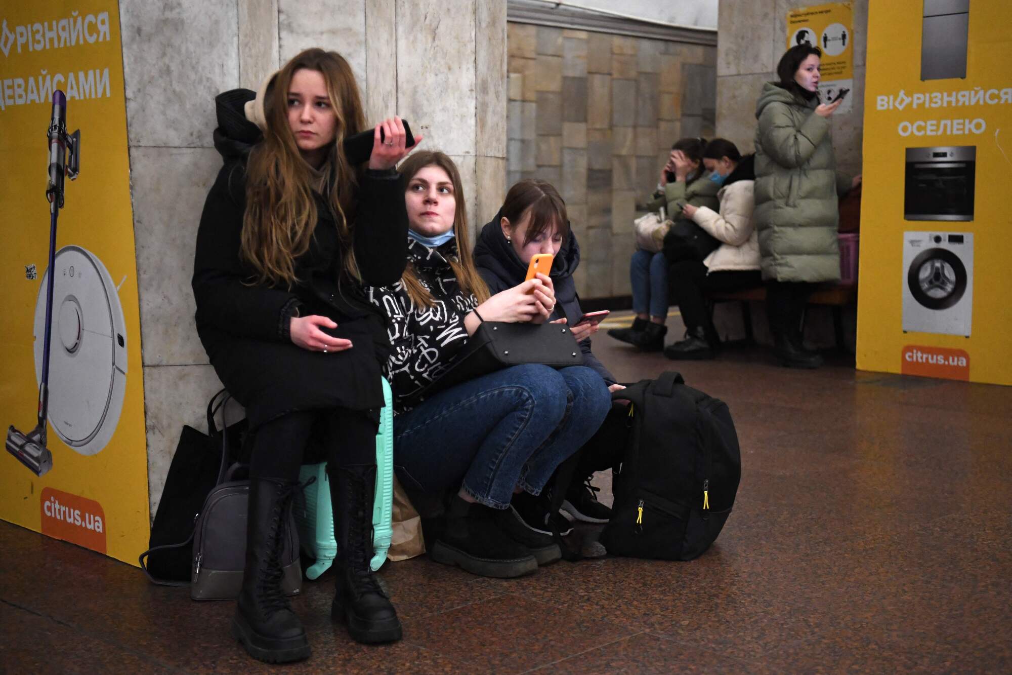 Girls hold their mobile phones as they take refuge in a Kyiv metro station