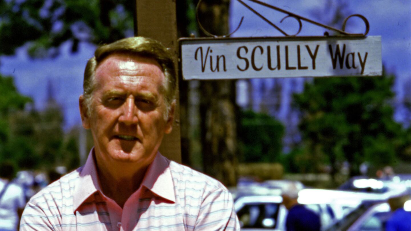 Vin Scully stands in front of street sign marking "Vin Scully Way" at the Dodgers' spring training complex in Vero Beach, Fla., in 1985.