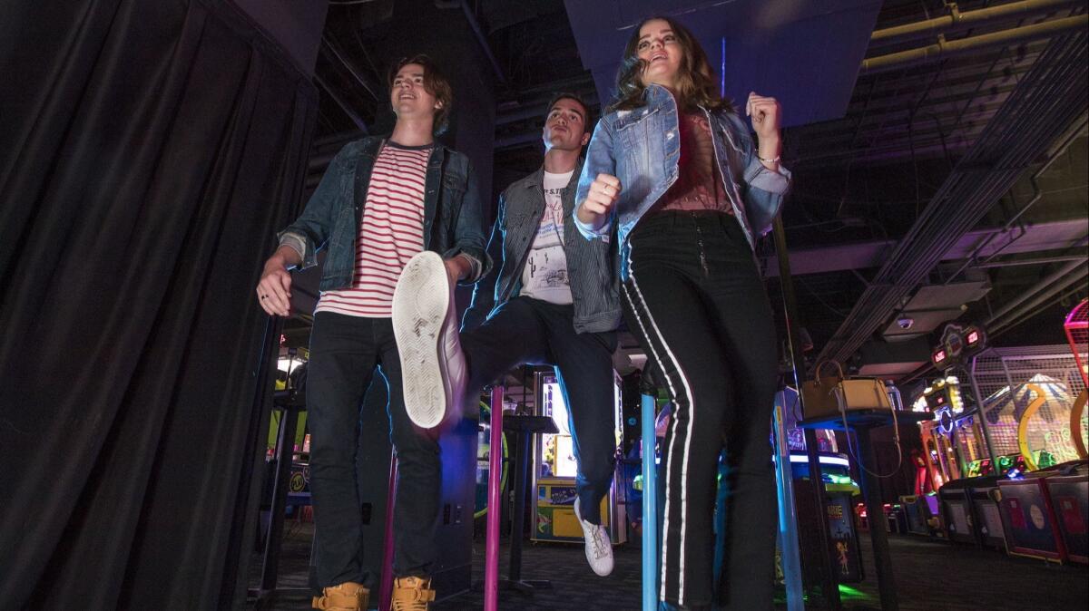 Courtney, left, Elordi and King play Dance Dance Revolution — a favorite game of the characters in "The Kissing Booth."