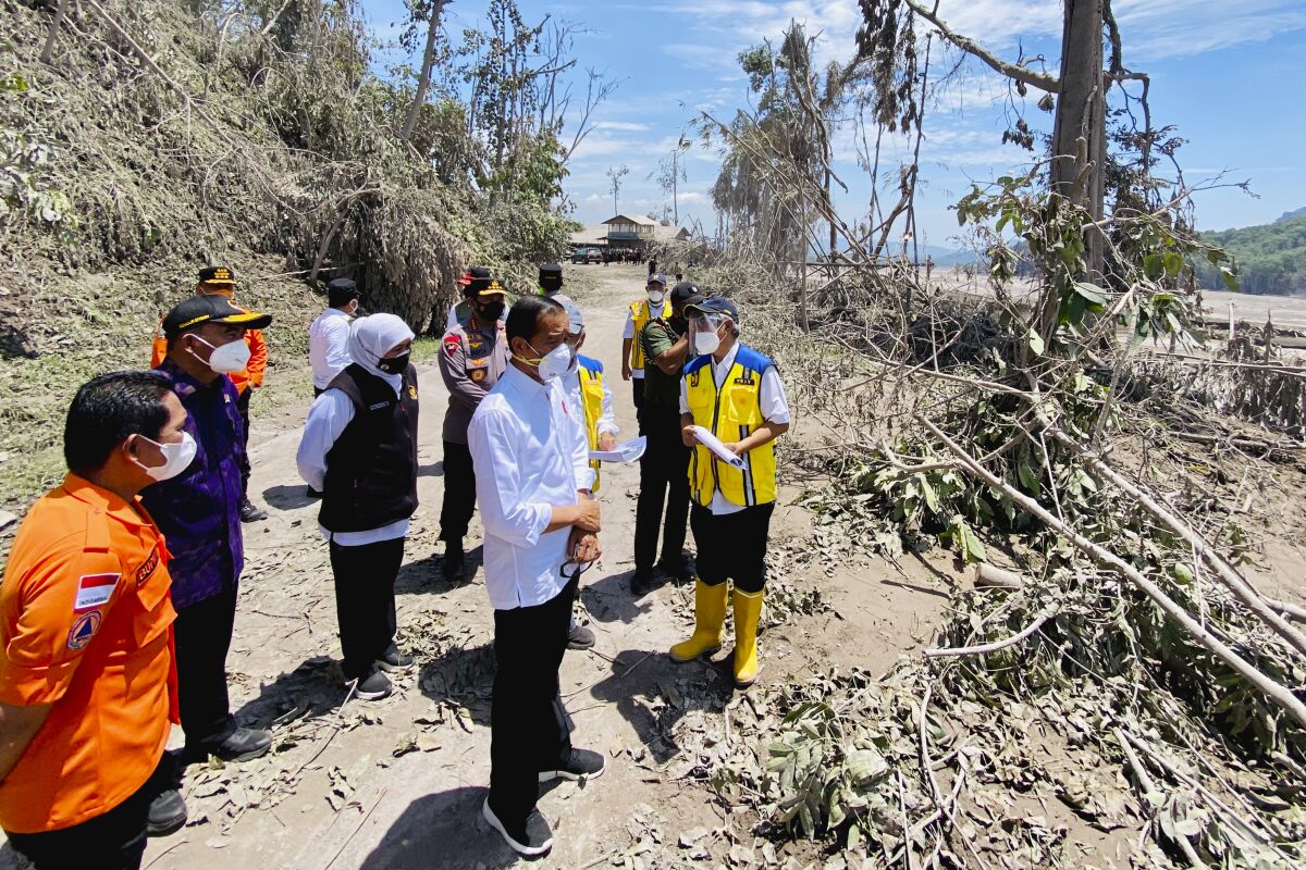 In this photo released by Indonesian Presidential Palace, Indonesian President Joko Widodo, center, inspects an area covered in ash from the eruption of Mount Semeru in Lumajang district, East Java province, Indonesia, Tuesday, Dec. 7, 2021. Widodo visited areas devastated by the powerful volcanic eruption that killed a number of people and left thousands homeless, and vowed that communities would be quickly rebuilt. (Indonesian Presidential Palace via AP)
