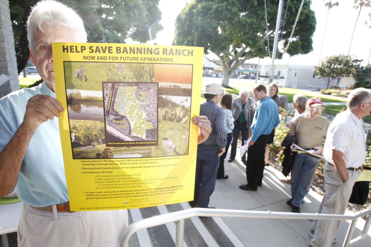 A woman against Banning Ranch development holds up a sign outside the Newport Beach City Council meeting last year.