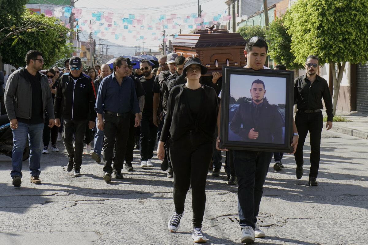 Men carry the coffin of one of the 12 people killed on a ranch 