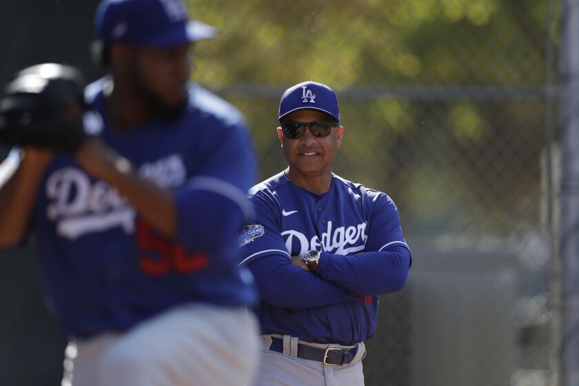 Los Angeles Dodgers manager Dave Roberts, right, looks on as relief pitcher Pedro Baez throws during spring training baseball Friday, Feb. 21, 2020, in Phoenix. (AP Photo/Gregory Bull)
