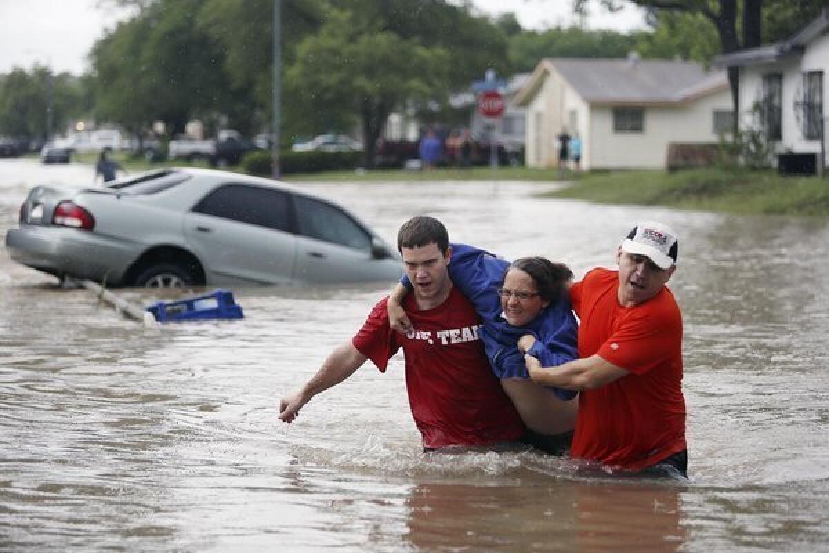 Marco Fairchild, left, and Gary Garza help Sueann Schaller from her car Saturday as floodwaters sweep San Antonio.