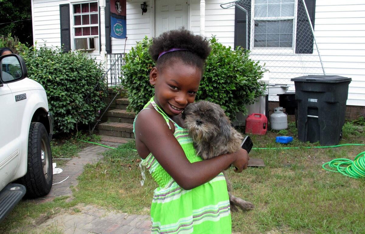 Regina Harrell, 9, holds her dog Roscoe outside her home in North Augusta, S.C. Regina was taken from her home and her mother charged with a felony after her mother, Debra Harrell, left her alone to play at a park while she worked at a nearby McDonald's.