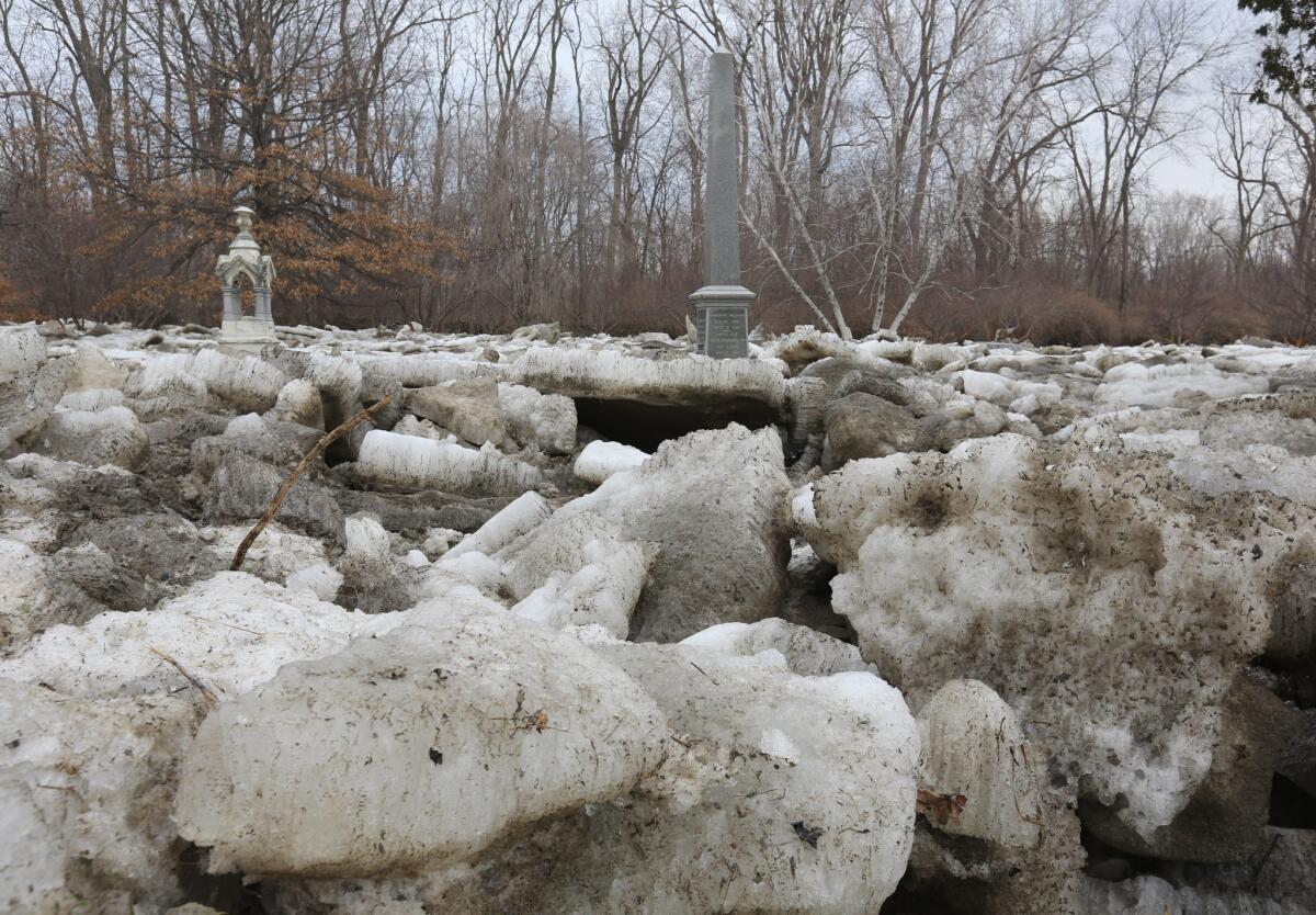 Two tall grave markers protrude from large chunks of ice piled in Riverside Cemetery in Maumee, Ohio, on March 16.