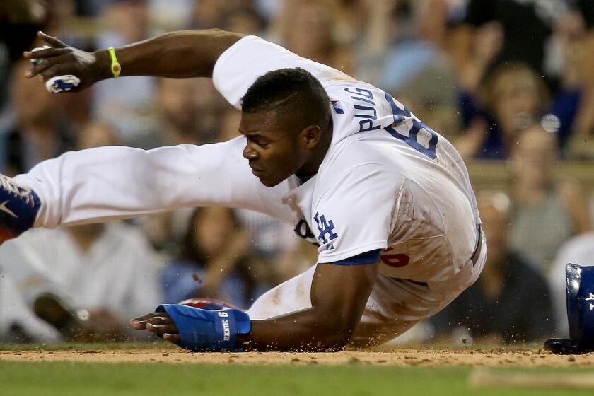 Dodgers center fielder Yasiel Puig tumbles past San Diego Padres catcher Yasmani Grandal (not pictured) to score a run in the third inning of the Dodgers' 4-1 loss Wednesday.
