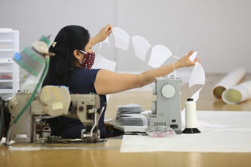 Esthela Gomez sews the second part of a face covering at the Ullman Sails workshop headquarters in Santa Ana.