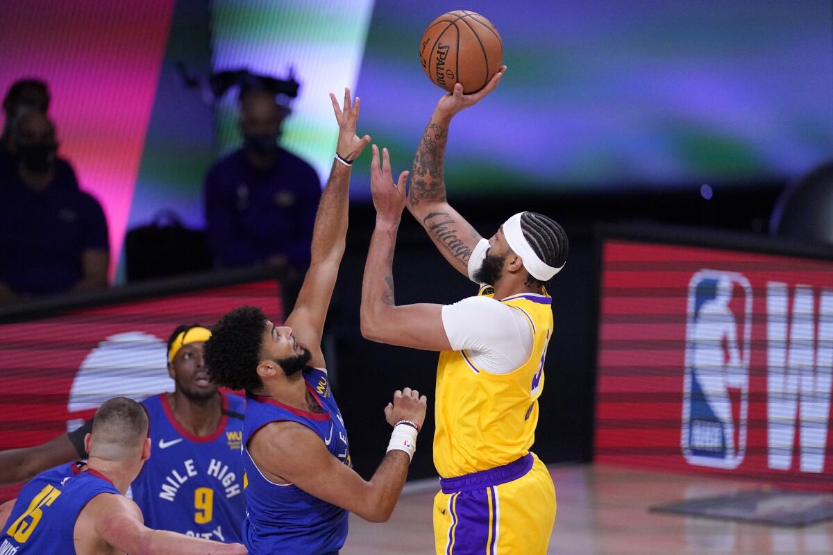 Lakers forward Anthony Davis attempts a shot over Nuggets defenders during Game 1.