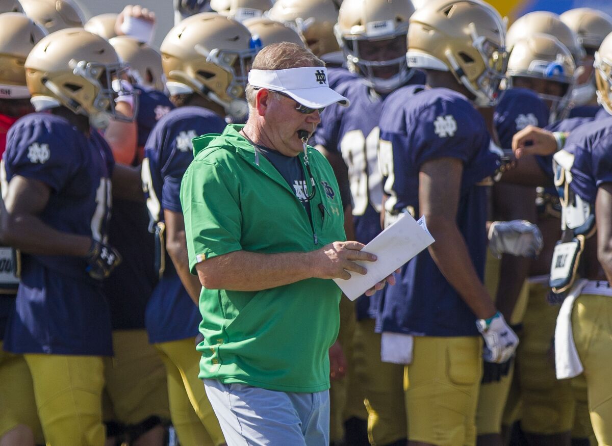 Notre Dame coach Brian Kelly looks at notes during a team practice session on August 8.