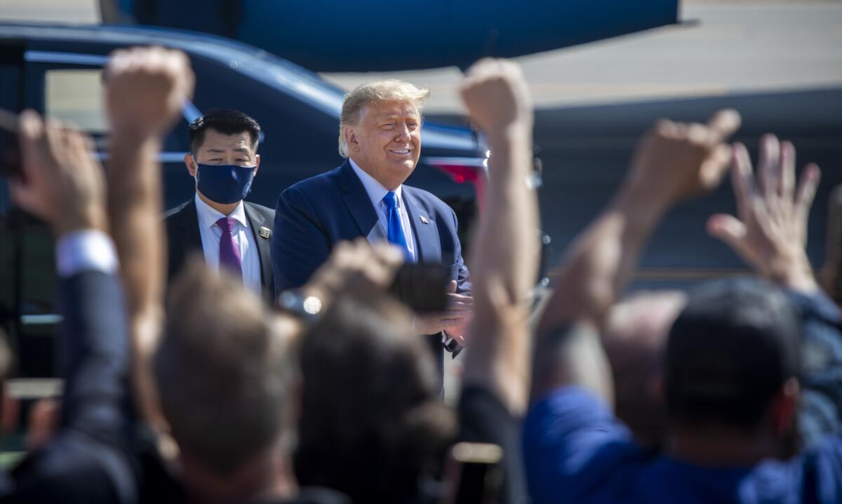 President Trump, outside at John Wayne Airport, smiles at supporters.