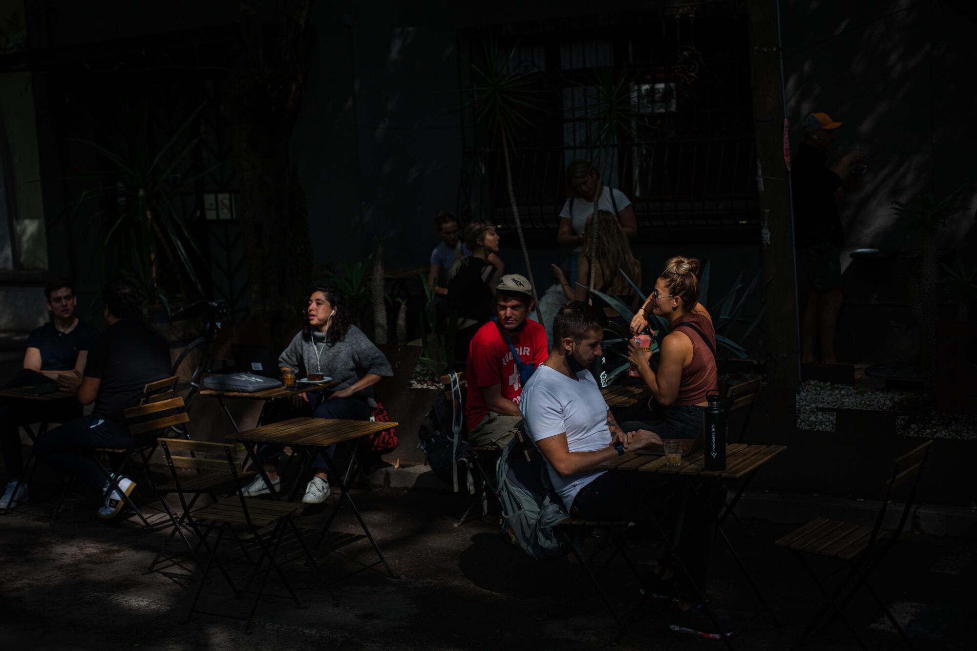 People sit at Quentin Cafe, a coffee shop popular with Americans and remote-workers