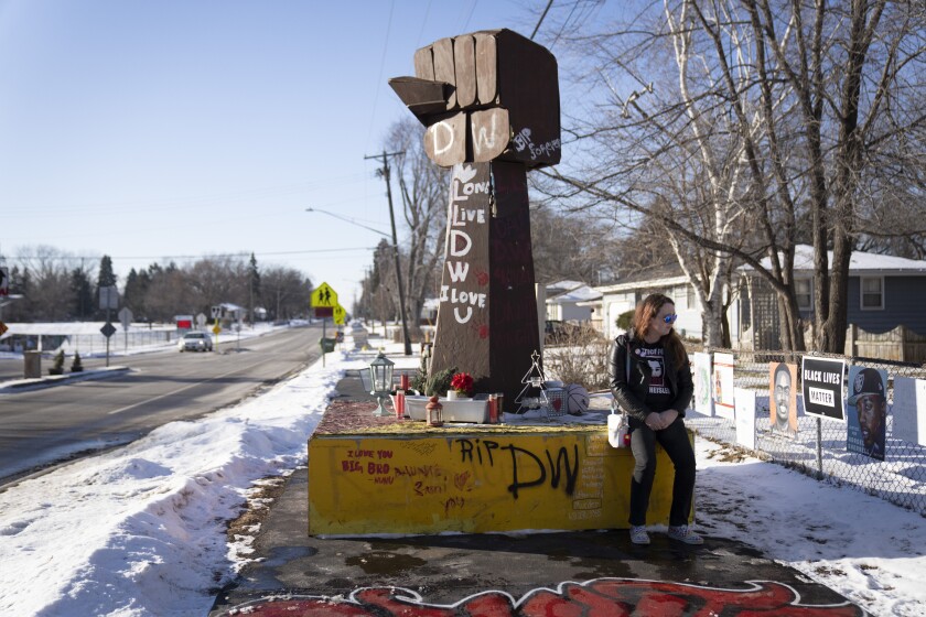 Zoey Seely, who lives in the neighborhood, sits at the memorial for Daunte Wright, after the guilty verdicts for Kimberly Potter were read on Thursday, Dec. 23, 2021, in Brooklyn Center, Minn. Plans to take down the memorial at the suburban Minneapolis intersection where Wright was fatally shot by a police officer are on hold after his family complained. (Renée Jones Schneider/Star Tribune via AP)
