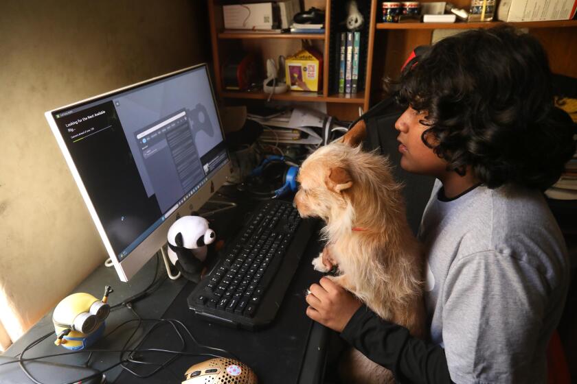 HUNTINGTON PARK, CA - APRIL 19, 2024 - 6th grader Luis Coronado, Jr., 12, spends time at his home computer which he used to do homework with support from his dog Candy in his family apartment in Huntington Park on April 19, 2024. "I don't know what the government is doing taking the Internet away from the kids," said Luis Coronado, Sr. about the end of Affordable Connectivity Program. The Coronado family will be some of the 700,000 people in Los Angeles County that will be effected when a federal internet subsidy program known as the Affordable Connectivity Program will run out of funds next week, leaving millions of Americans without internet access. (Genaro Molina/Los Angeles Times)