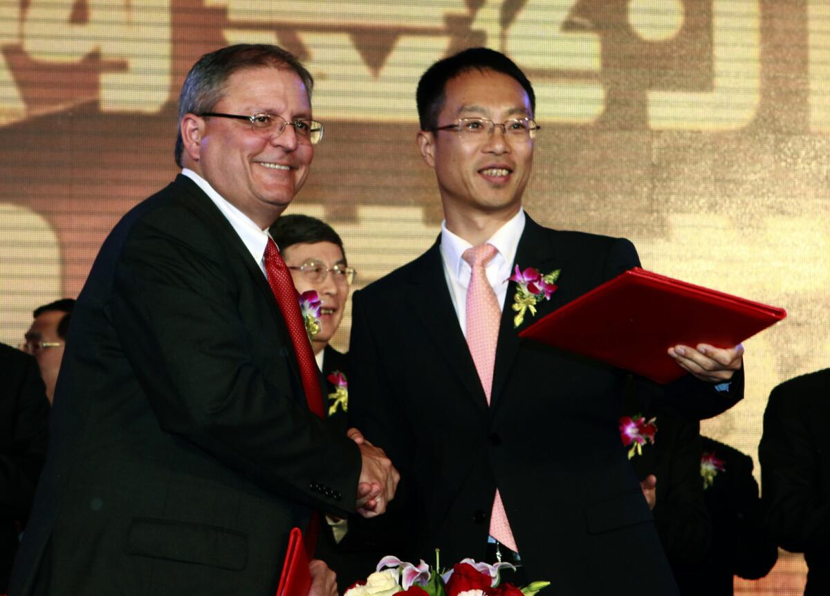 Gerry Lopez, chief executive of AMC Entertainment Holdings, left, shakes hands with Zhang Lin, vice president of Dalian Wanda Group, during a Beijing signing ceremony for Dalian Wanda to acquire AMC Entertainment.
