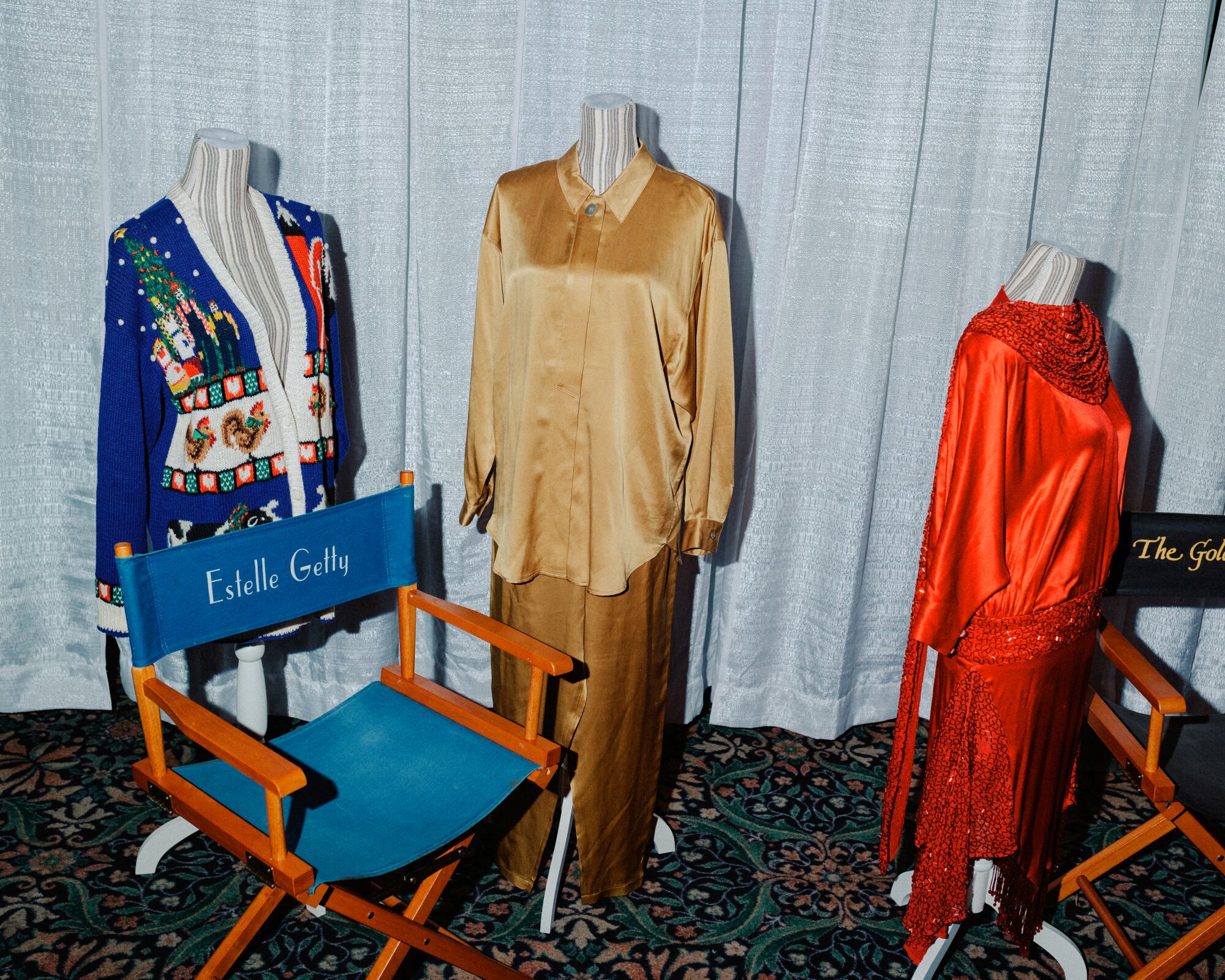 Red, gold and holiday-themed outfits next to director's chairs.