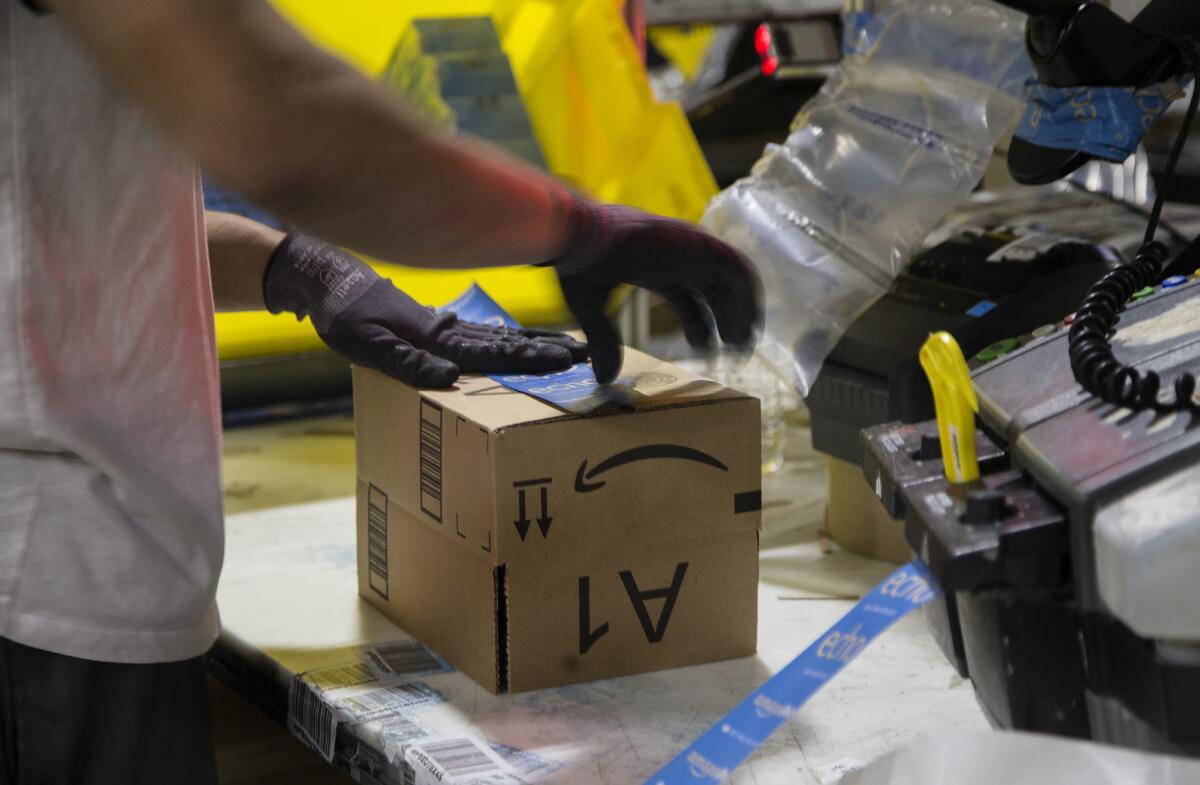 A worker tapes a box while packing items at the Amazon Fulfillment Center in San Bernardino.