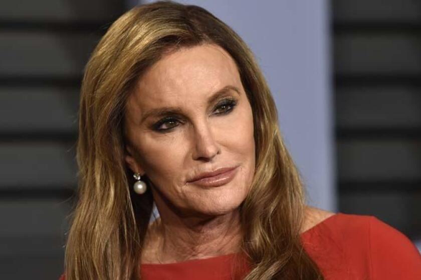 Caitlyn Jenner posing in pearl earrings and a red dress