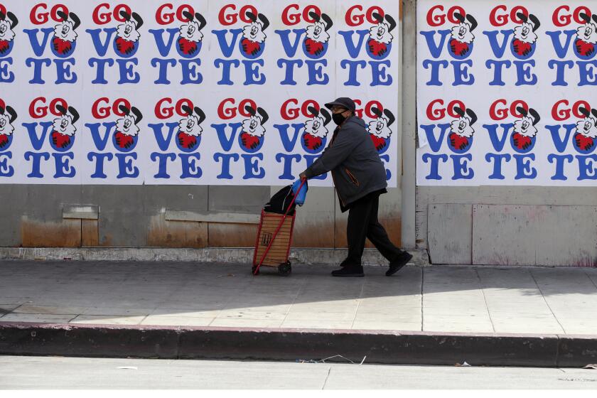 LOS ANGELES, CA - NOVEMBER 03: A man walks Go Vote mural on Broadway in front of Grand Central Market on Tuesday, Nov. 3, 2020 in Los Angeles, CA. (Irfan Khan / Los Angeles Times)