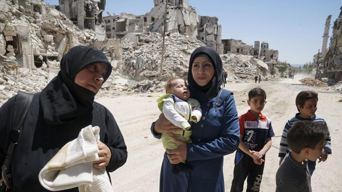 Sabah Sheikh Ali, 29, holds her two-month-old son Taim, accompanied by her mother-in-law Souad Rasheed, 60, and other children. Their former family home in Aleppo’s Salahuddin neighborhood is now rubble.