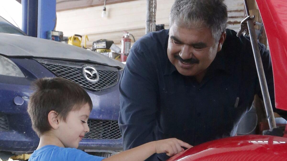 Rubén Moroyoqui habla con su hijo Rafael en su taller de reparaciones de automóviles en Tucson, Arizona. Moroyoqui fue reportado a las autoridades de inmigración tras ser detenido mientras recogía con su vehículo piezas de automóviles.