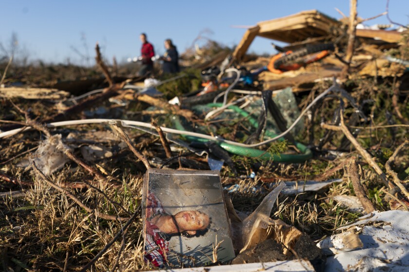 A family photograph lies among the debris along Moss Creek Avenue in Bowling Green, Ky., Tuesday, Dec.14, 2021. The neighborhood was one of the hardest hit areas in the city after a tornado ripped through the weekend before. (AP Photo/James Kenney)