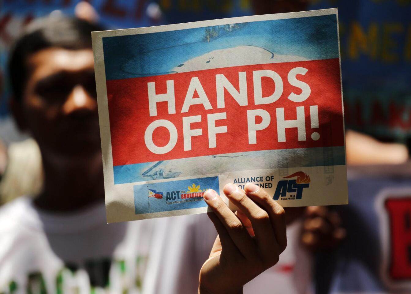 A Filipino holds a placard reading "Hands Off PH!" while protesting outside the Chinese consular office in Makati, near Manilla, against China's territorial claims over the disputed Spratly Islands.