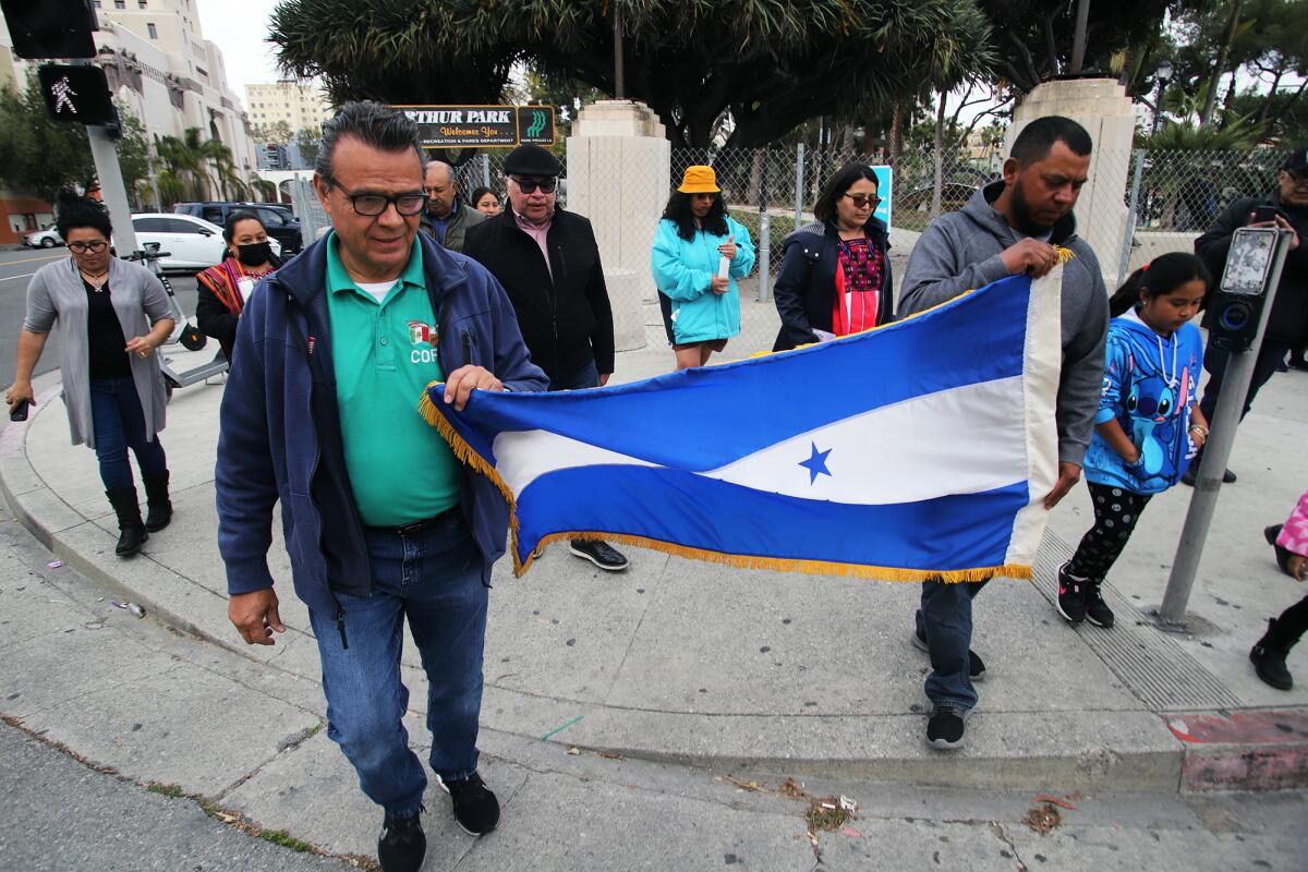 A group of people from Central America and Mexico hold the Honduras flag