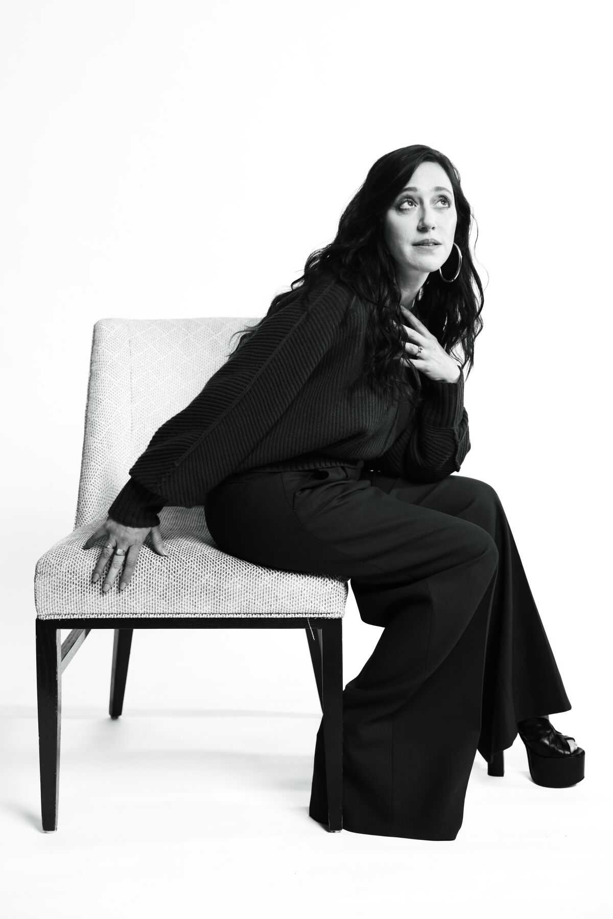 Actor Mariana Trevino sits on the side of a chair, eyes raised skyward for a portrait.