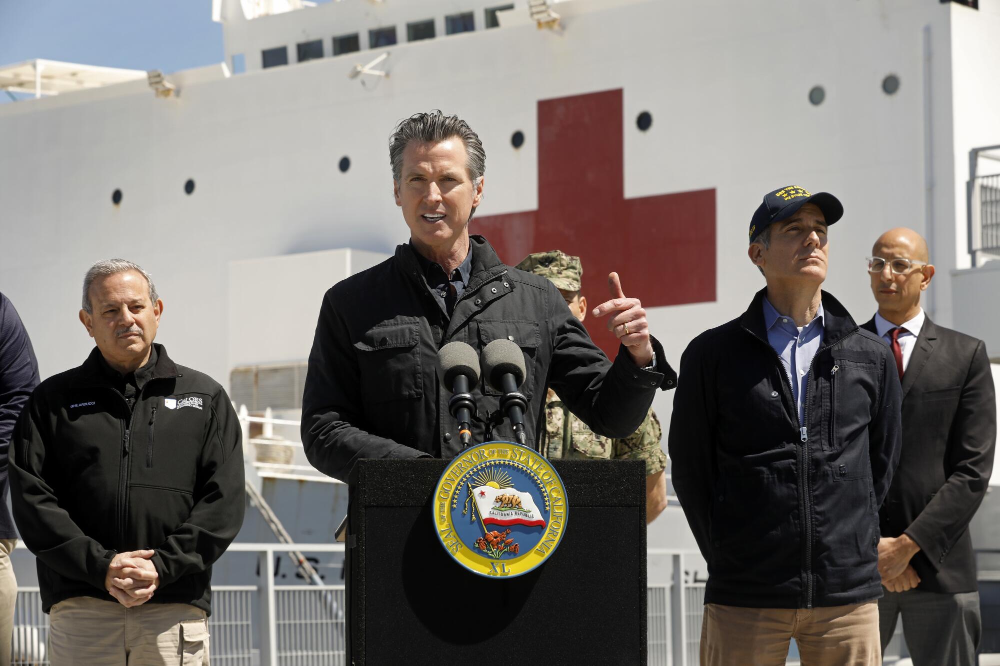 California Gov. Gavin Newsom speaks in front of the Navy hospital ship Mercy after its arrival into the Port of Los Angeles on Friday. Director Mark Ghilarducci of the Office of Emergency Services, left, L.A. Mayor Eric Garcetti and California Secretary of Health and Human Services Dr. Mark Ghaly also attended.