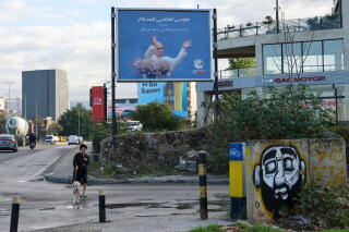 A woman walks her dog past a billboard displaying a picture of a man in white religious robes