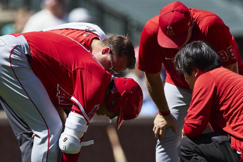 Los Angeles Angels designated hitter Shohei Ohtani is visited by trainers before.