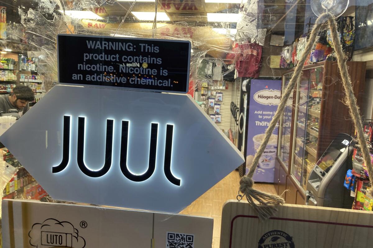 A Juul sign hangs in the front window of a convenience store.