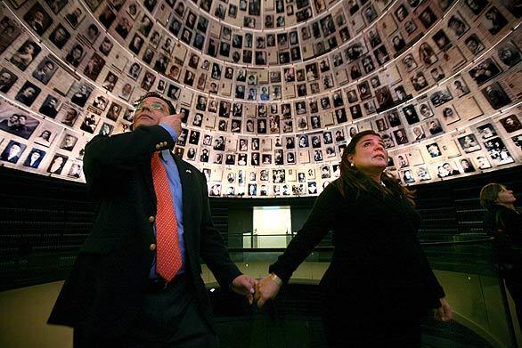 Marisol Argueta de Barillas, El Salvador's foreign minister, holds her husband's hand while looking at photographs of Holocaust victims at Yad Vashem, the Holocaust memorial museum in Jerusalem. De Barillas later took part in a ceremony honoring the Jews killed by the Nazis during World War II.