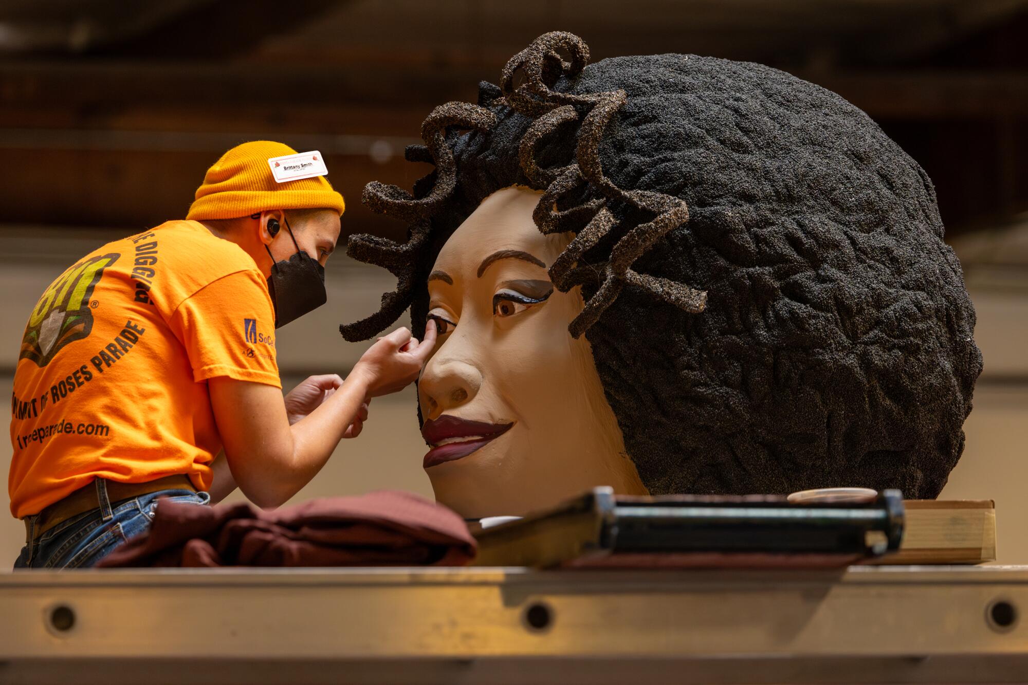 Brittany Smith works on the Kaiser float for the 2024 Rose Parade at Fiesta Parade Floats in Irwindale.