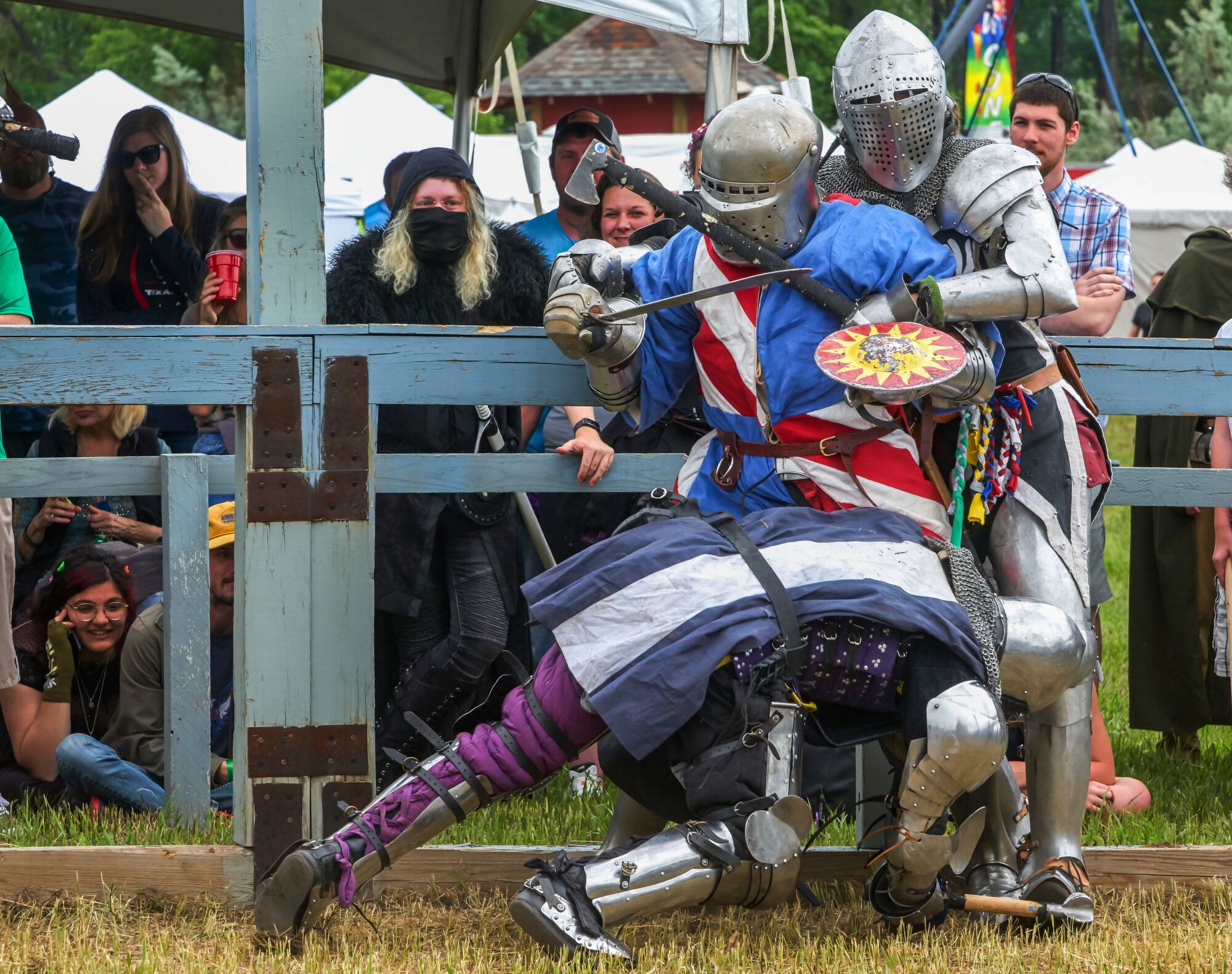 Three fighters in medieval-style armor try to bring one another down. 