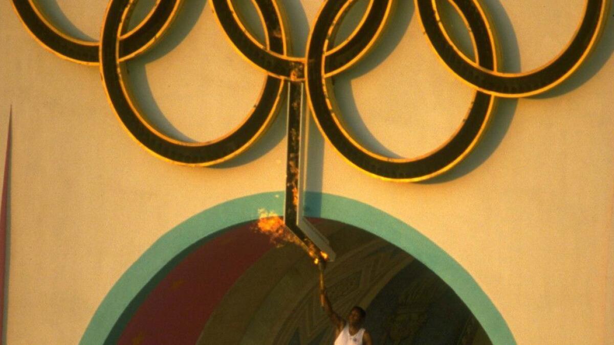 Rafer Johnson holds the Olympic torch after lighting the Olympic flame during the opening ceremonies for the 1984 Olympics