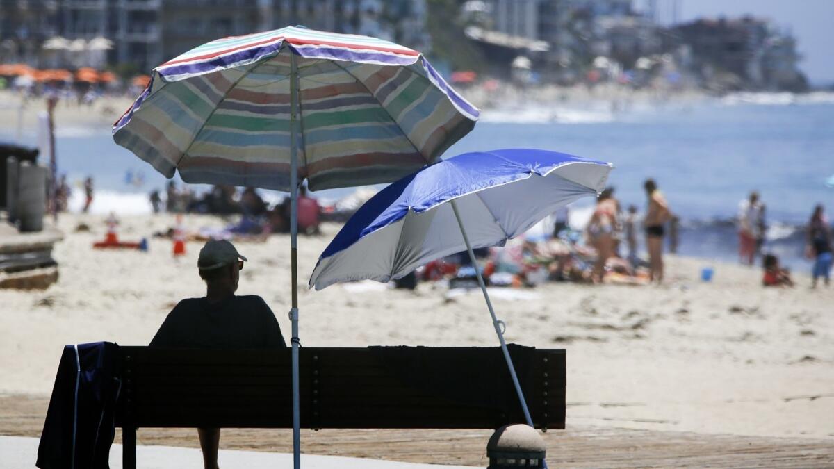 A low-pressure system moving into Southern California will bring lower temperatures following days of above-average heat. In this 2017 file photo, beachgoers hit the sand in Laguna Beach.