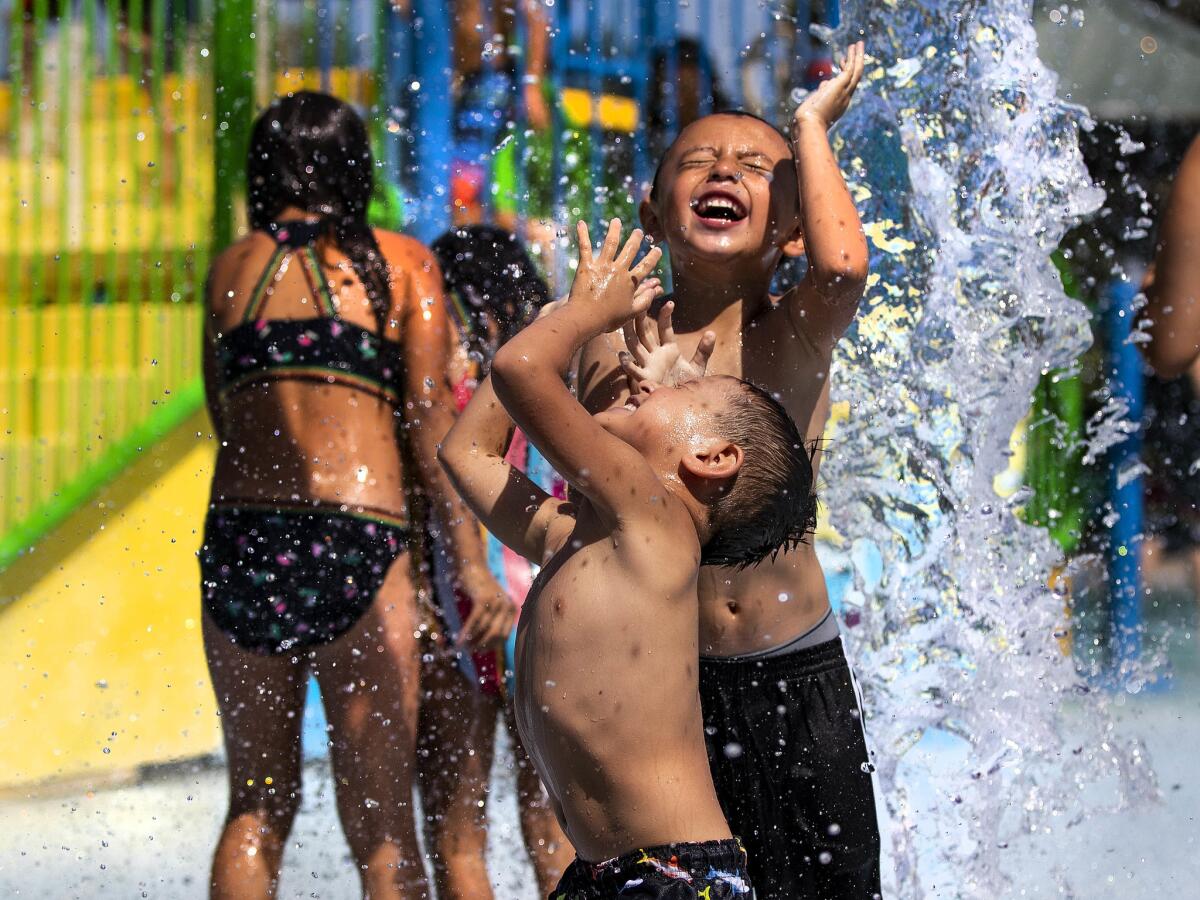 Mayson Huerta, 4, left, and his cousin Sebastian Vela, 6, of Riverside stay cool at the water park inside Rancho Jurupa Park campground in Riverside.